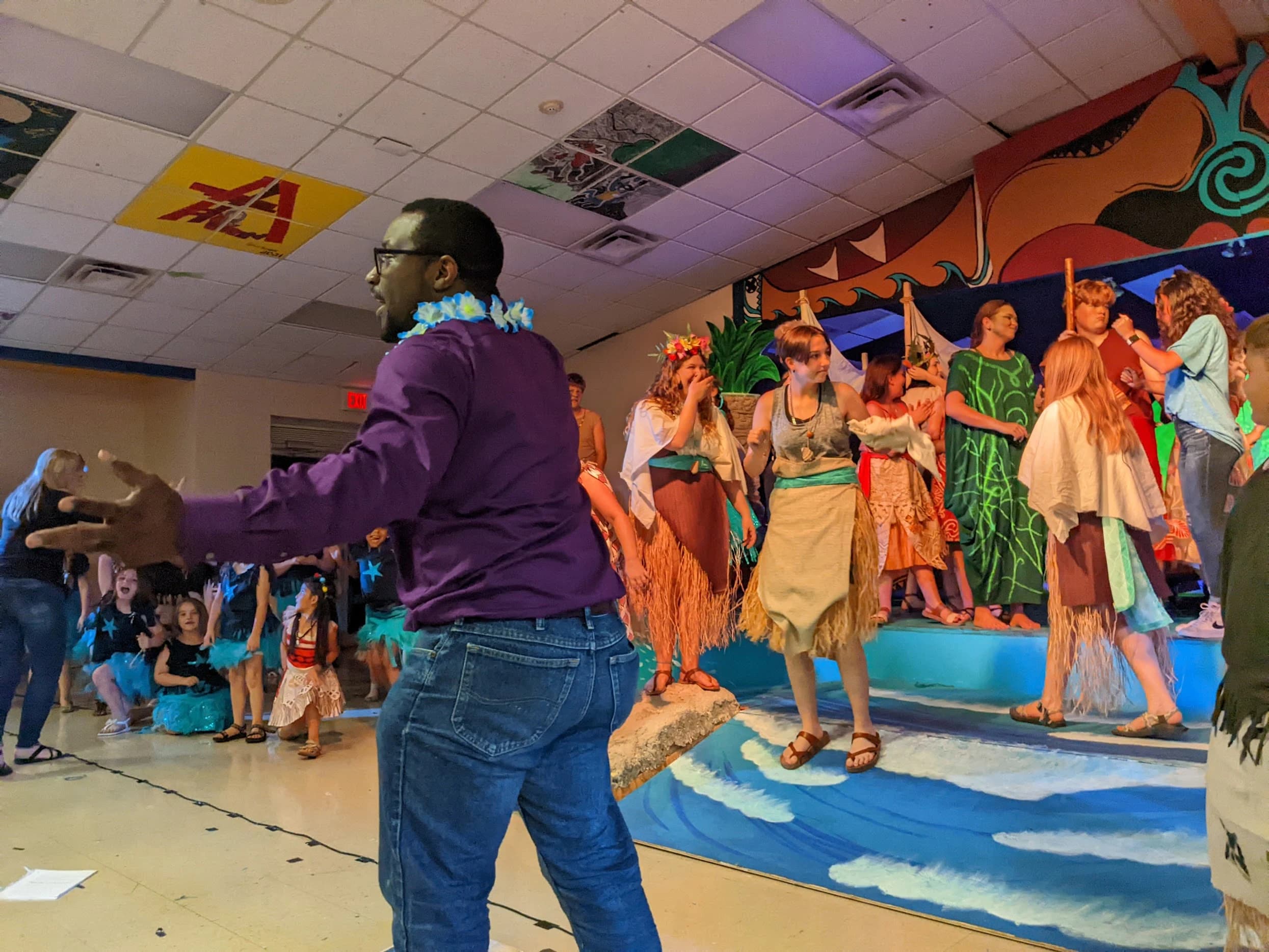 Jason Wright directing the Moana cast, arms spread wide