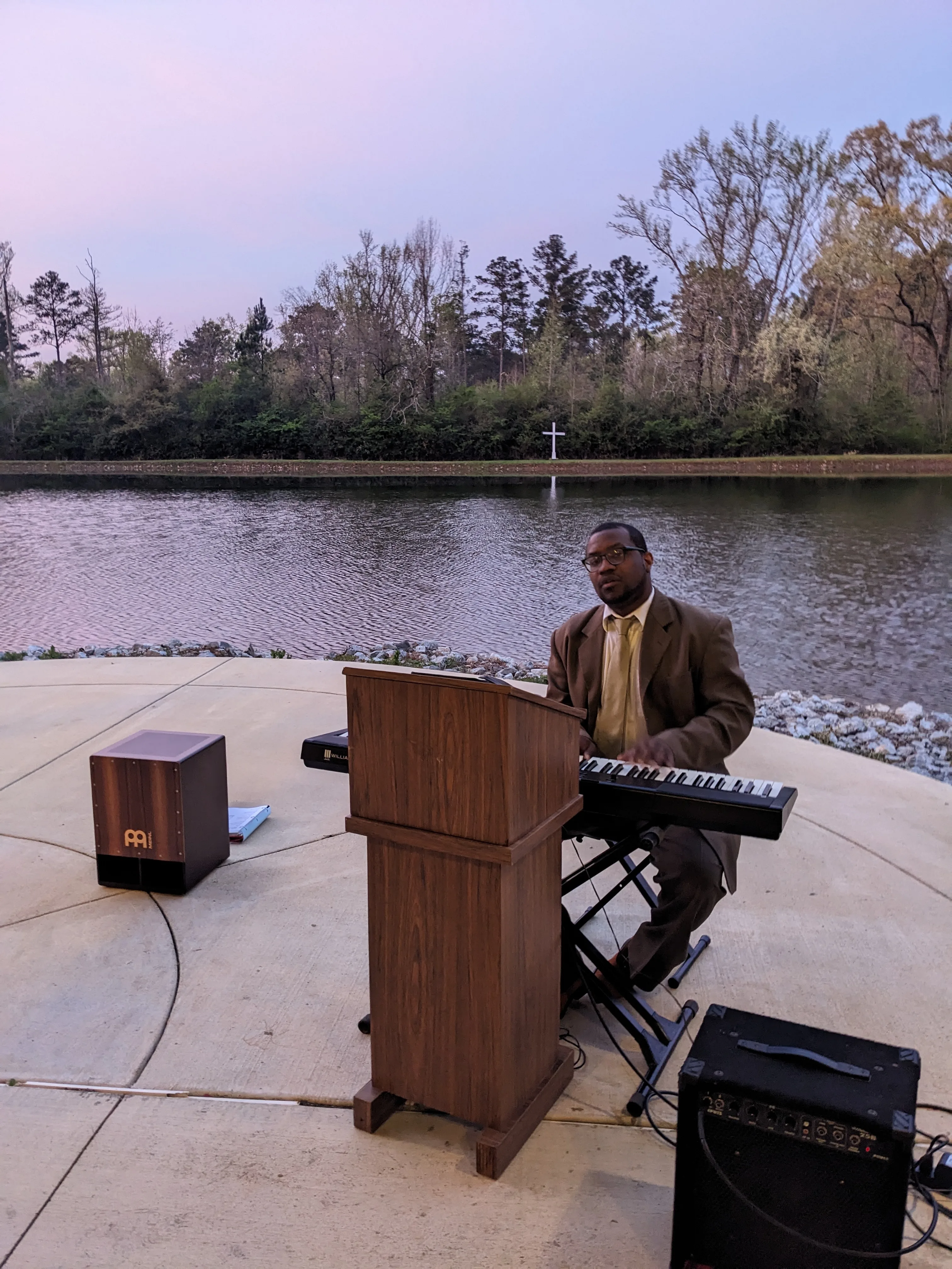 Jason Wright playing keyboard at an outdoor lakeside venue at dusk